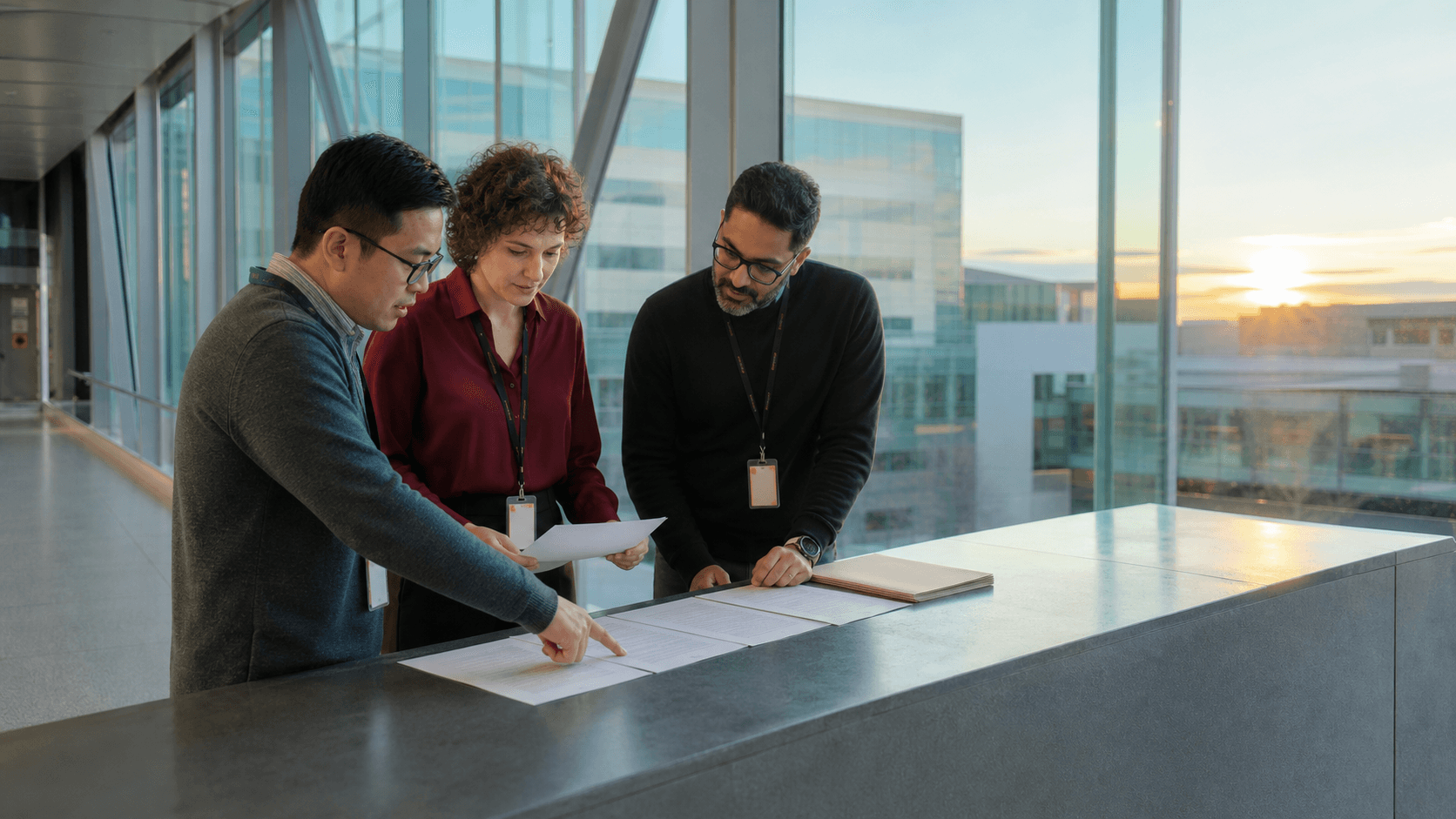 Three academic researchers organize generic manuscript pages in a university hospital skybridge.